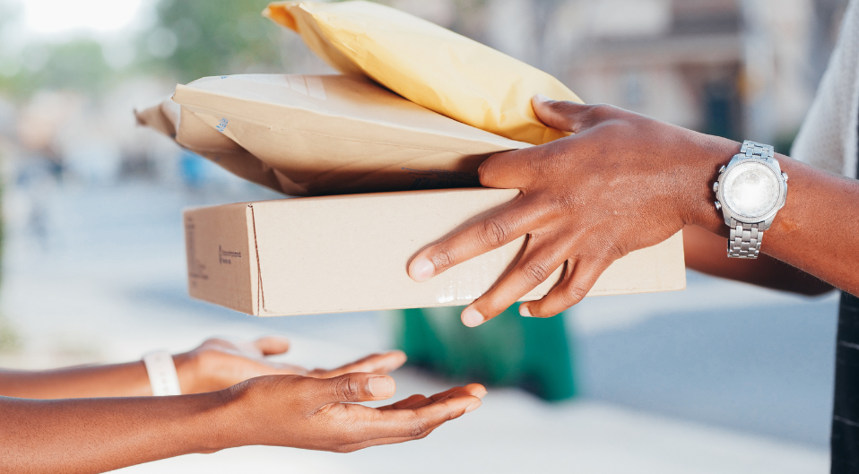 The hands of two people reaching out to exchange several parcels