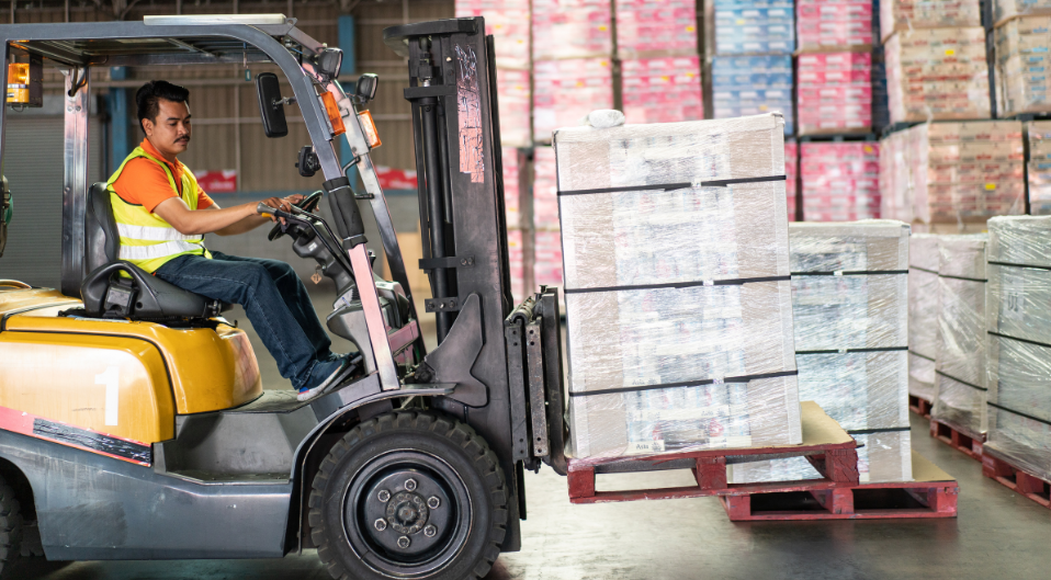 man on forklift moving pallets in warehouse
