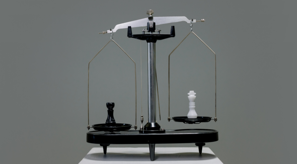 A set of weighing scales with a black weight on on side and a white weight on the other