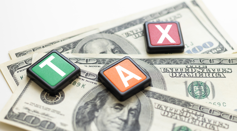 wooden blocks spelling 'tax' spread on top of american currency